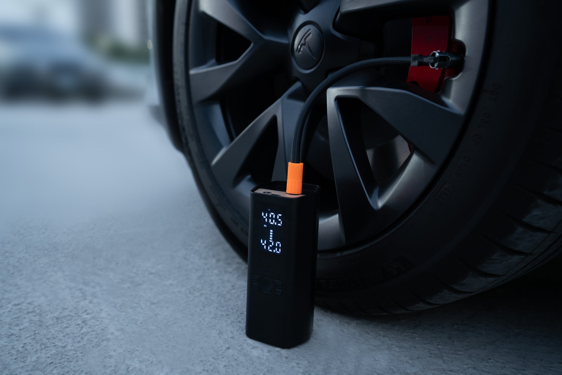 The JOWUA Portable Air Compressor + Charging Solution Kit connects to Tesla tires, showing real-time tire pressure on its screen while quickly and efficiently inflating them.