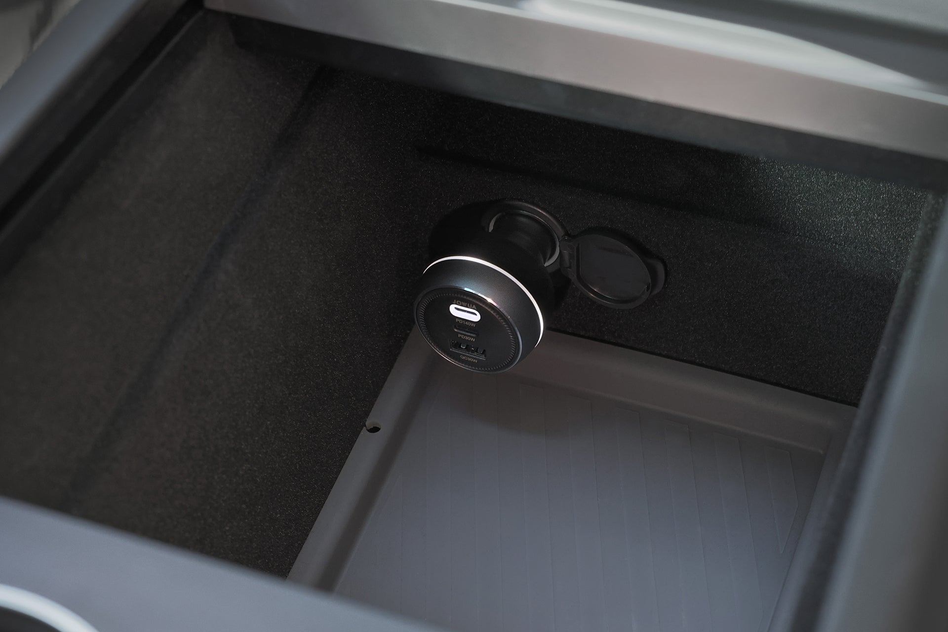 Close-up of JOWUA Portable Air Compressor + Charging Solution Kit’s center console storage, showing a circular USB charging port with USB-A and USB-C outlets for fast charging. Compartment has dark felt lining and a removable plastic mat.