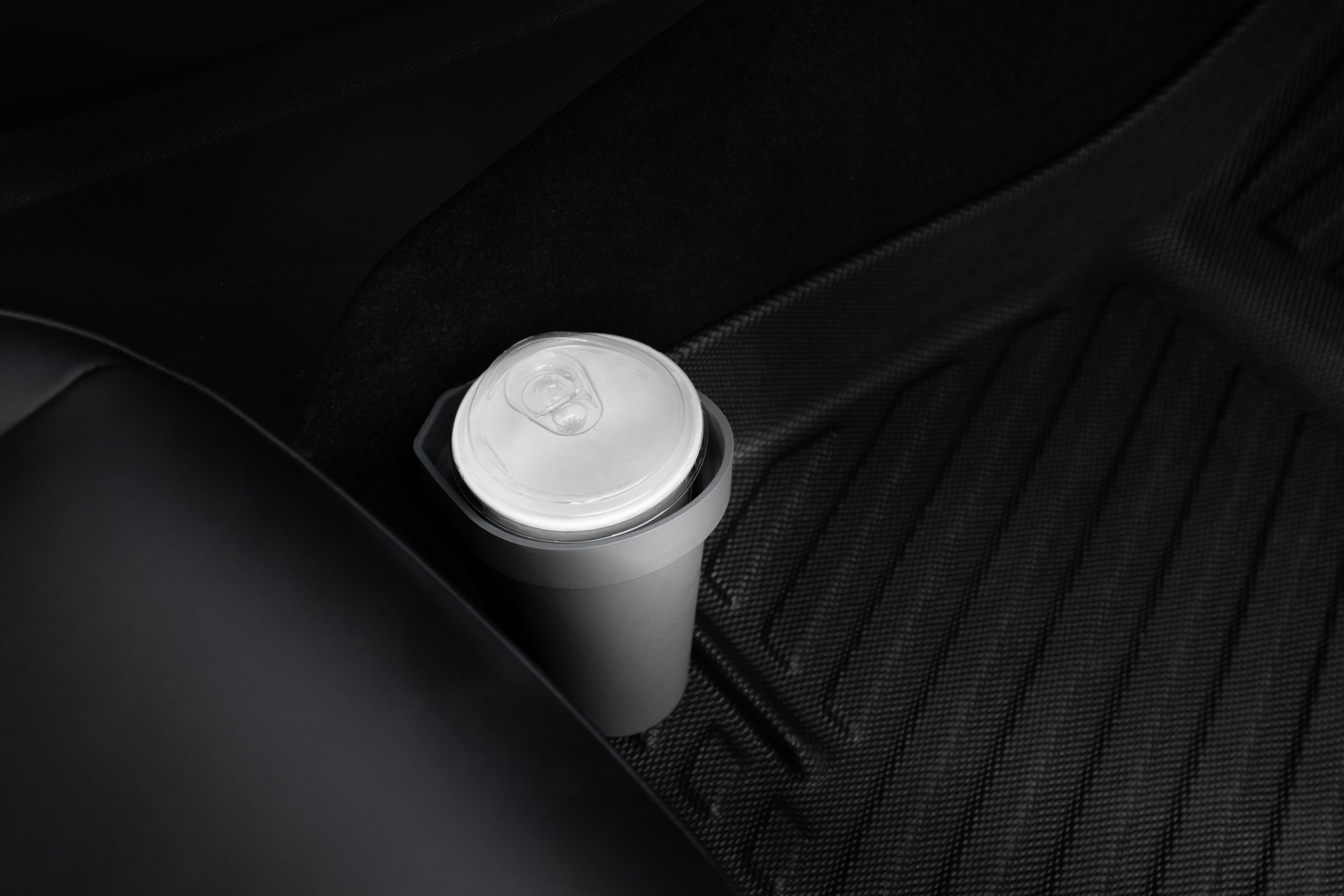 A takeaway coffee cup with a plastic lid is placed on a JOWUA Door Side Storage Box, crafted from silicone material, next to the sleek black leather seat of a Tesla Model S.