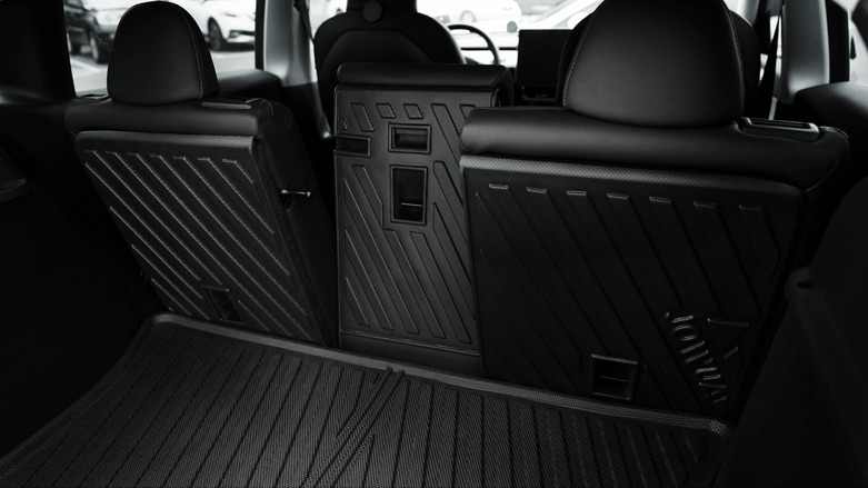 Back view of a car's interior focusing on the folded rear seats, displaying a modern and sleek design with textured surfaces. The seats are folded to maximize cargo space.