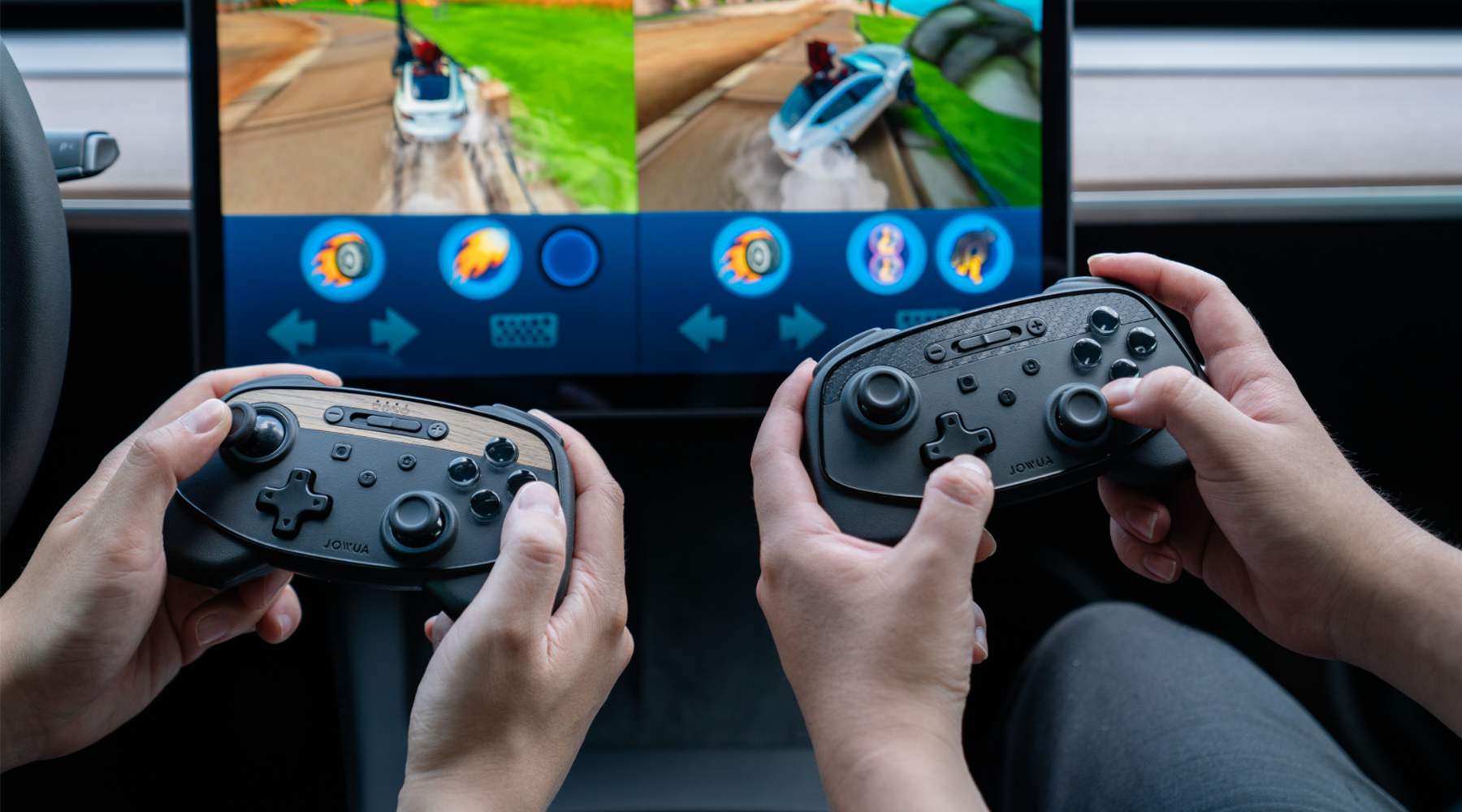 Two individuals holding wireless game controllers are playing a racing video game on a split-screen display. The screen shows colorful, animated race tracks with icons and controls visible on the screen.