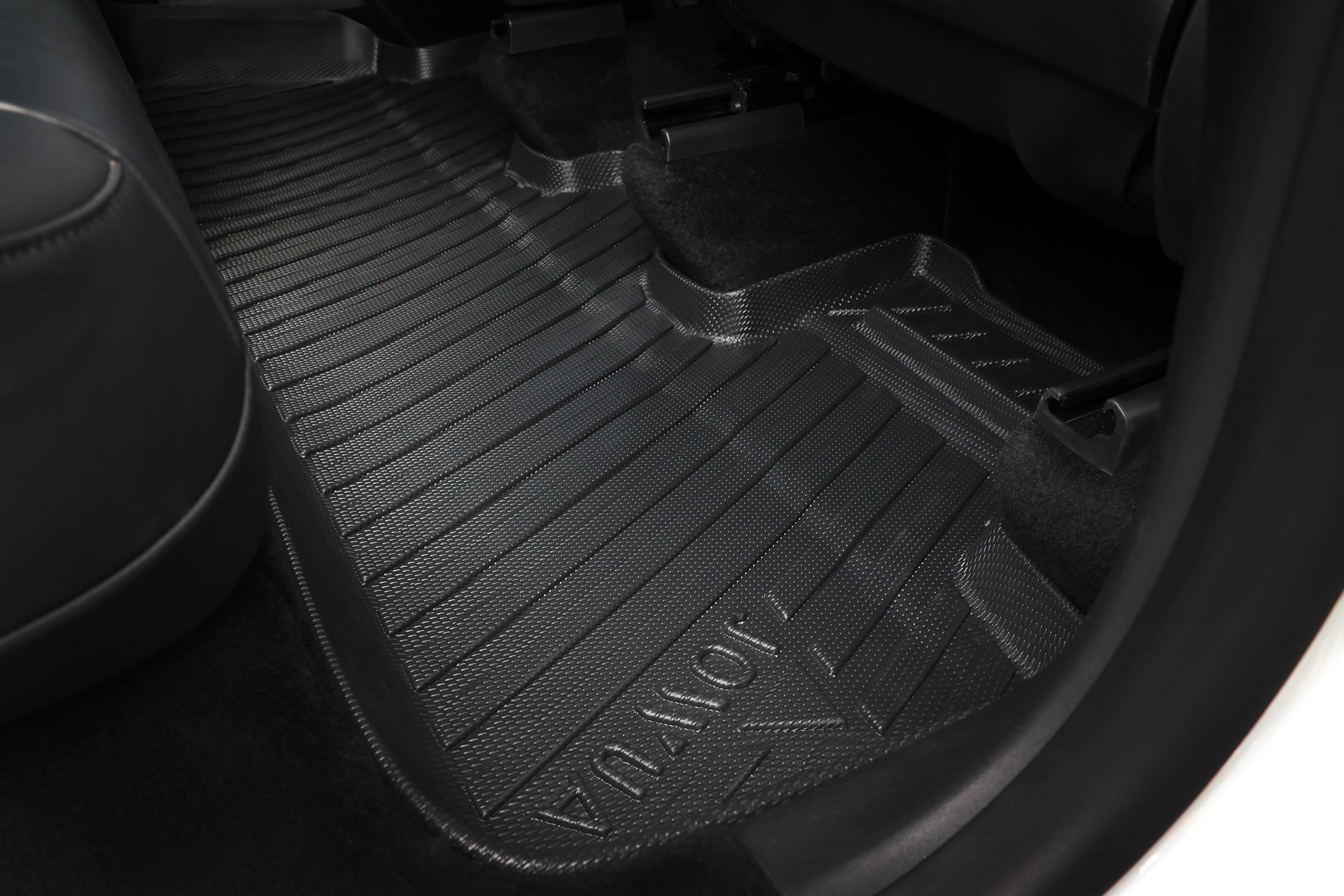 Close-up of a JOWUA Premium Interior Essentials Set (RHD) floor mat for Model Y Juniper (2025+), shown with textured black finish and embossed branding on the rear floor of a right-hand drive car with a black interior.