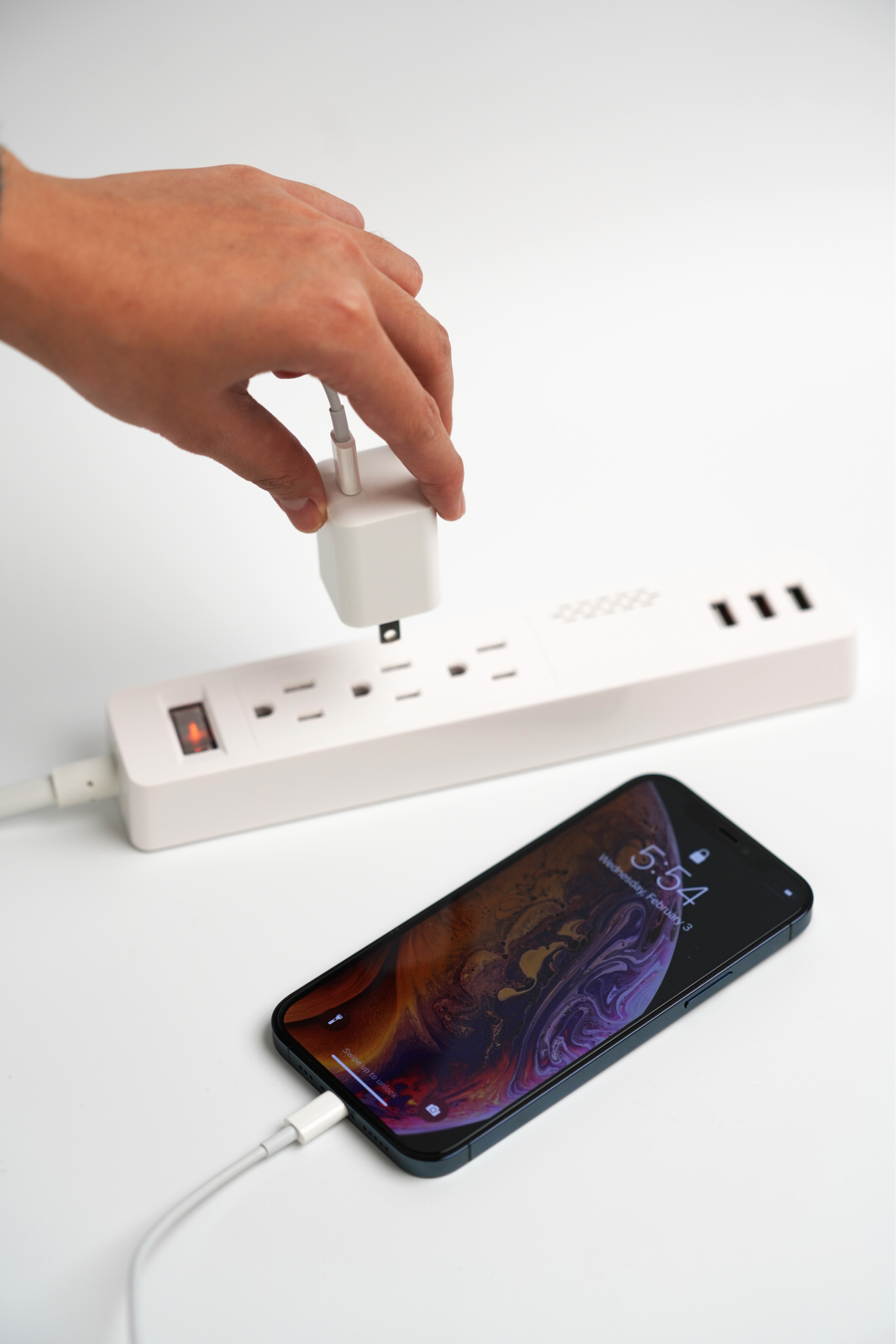 A person connects a 20W USB-C Mini Power Adapter from JOWUA, known for its sleek and compact design with multiple outlets and USB ports. Nearby, a smartphone is linked to the power adapter using a QC 3.0 charging cable, with the screen showing the time 5:54 against a plain white background.